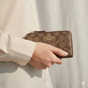 A person holding a coach medium zip wallet to demonstrate its compact size and portable design.
