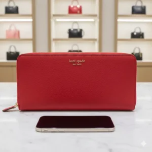 Side-by-side size comparison of a large wallet kate spade next to a smartphone.