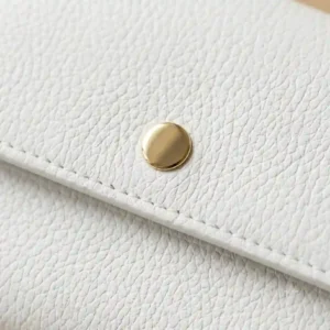 Close-up of the pebbled leather texture and durable stitching on a luxury white wallet.