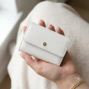 A person holding a slim white wallet to demonstrate its compact size and daily portability.
