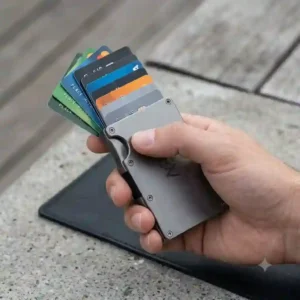 A hand triggering the quick-access ejector mechanism on a metal slimline wallet to fan out credit cards.